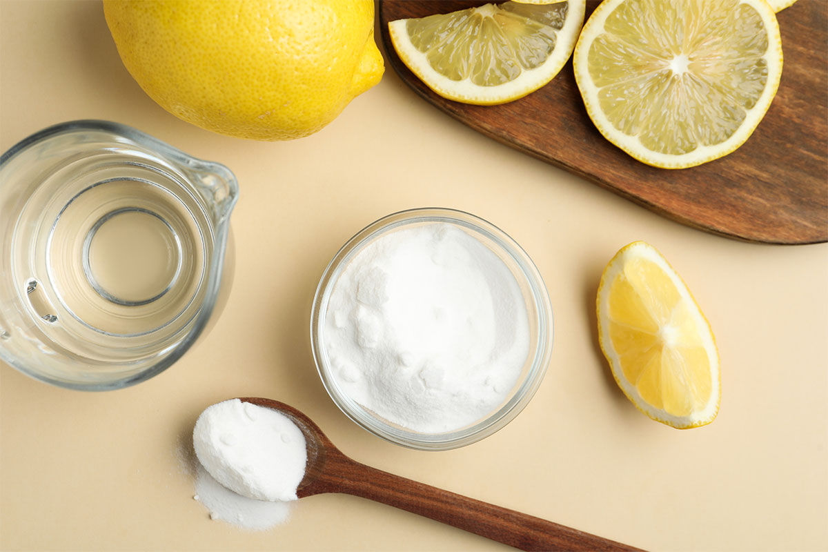 lemons, baking soda, and water on a light yellow background