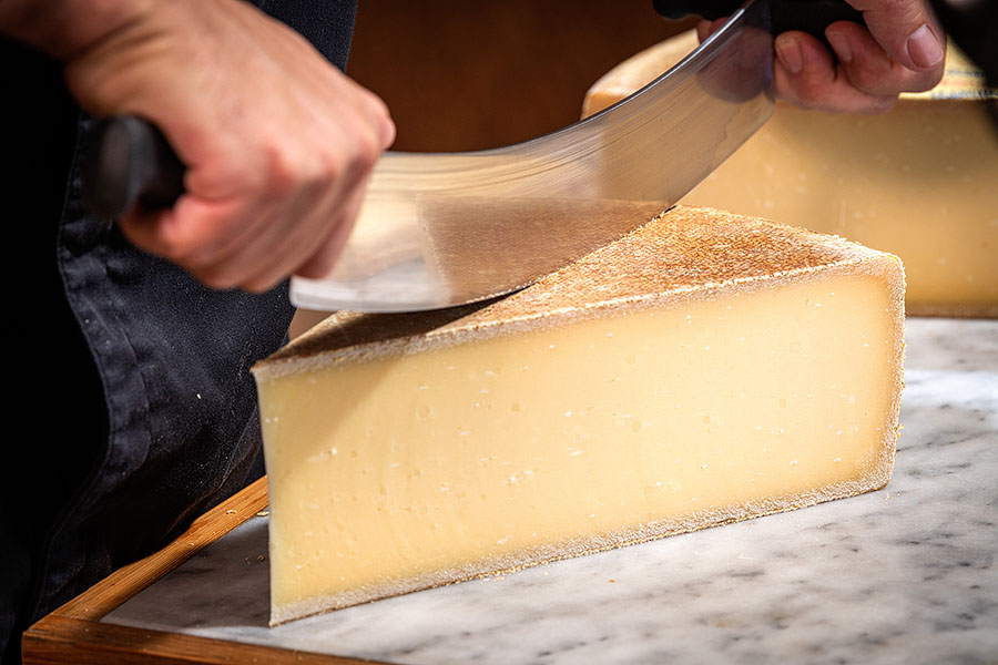 Gruyère cheese being cut with a big knife